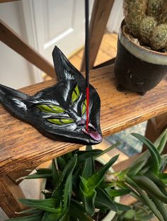 a cat mask sitting on top of a wooden bench next to a potted plant