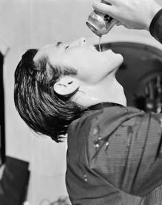 a young man is drinking from a water faucet in front of a sink