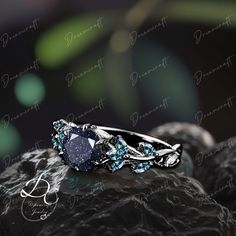 a blue diamond ring sitting on top of a rock