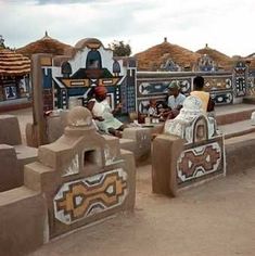 some people are sitting on benches made out of clay