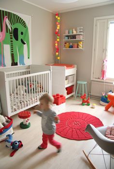 a toddler running through a room with lots of toys on the floor and walls