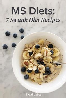 a bowl filled with nuts and blueberries next to a spoon on top of a table