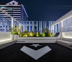 an empty parking lot with plants growing on the roof and in the background, buildings are lit up at night