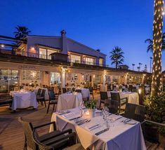 an outdoor dining area with tables, chairs and lights on the side of the building