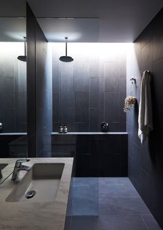 a bathroom with black walls and tile flooring, along with a sink in the middle