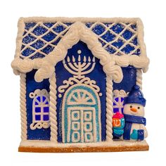 a blue and white gingerbread house with a snowman next to it on a table