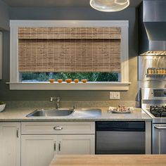 a kitchen with a sink, stove and window covered in bamboo blind shades on the windowsill