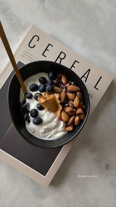 a bowl of cereal with yogurt, blueberries and almonds on top