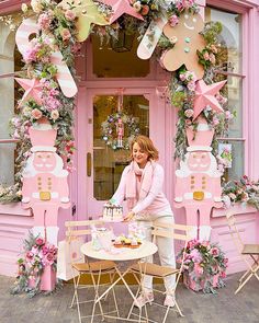 a woman sitting at a table in front of a pink building with decorations on it