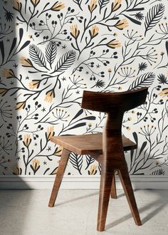 a wooden chair in front of a floral wallpaper