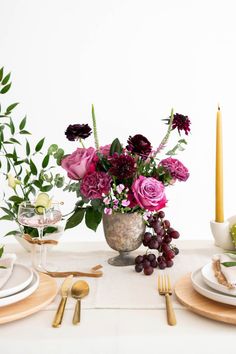 the table is set with plates, silverware and flowers