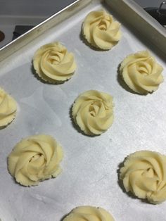 nine cupcakes with frosting sitting on a baking sheet ready to go into the oven