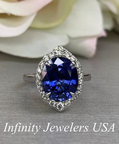 an oval shaped blue sapphire surrounded by white diamonds in a halo setting with the words infinity jewelers usa above it