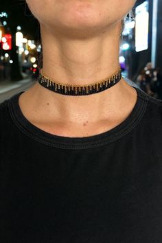 a close up of a person wearing a black and gold choker on their neck