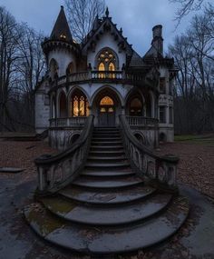 an old castle like building with stairs leading up to the front door and windows at night