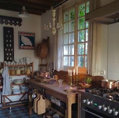 a kitchen with an oven, stove and table in front of a window filled with pots and pans