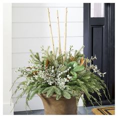 a potted plant with white flowers and greenery in front of a black door