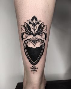 a woman's leg with a heart and flower tattoo on the lower part of her leg