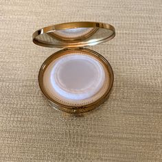 an open gold ring case sitting on top of a tan tablecloth covered flooring