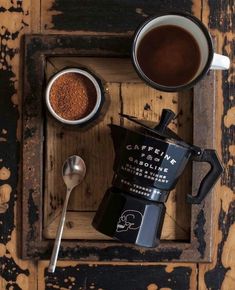 two cups of coffee and spoons on a wooden tray