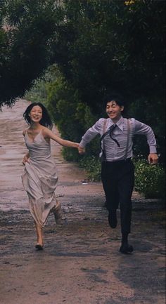 a man and woman walking down a dirt road holding hands