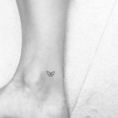 a small butterfly tattoo on the ankle is seen in this black and white photo,