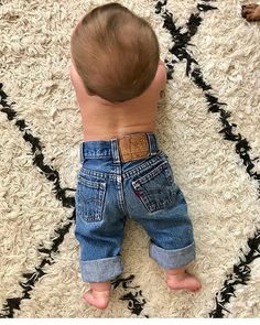 a baby laying on top of a white rug