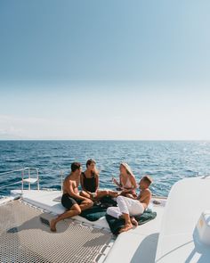 four people sitting on the deck of a boat