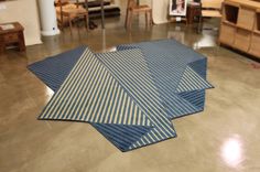 three pieces of blue and white striped rugs on the floor in a room with furniture