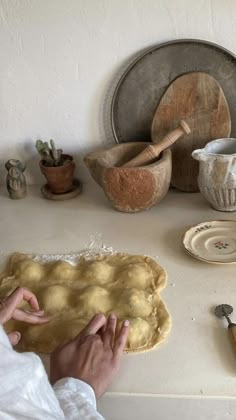 a person is kneading dough on top of a table with other kitchen items