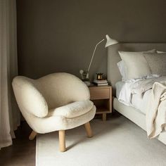 a white chair sitting next to a bed in a bedroom