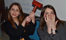 two young women with painted nails holding up hammers