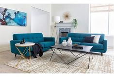 a living room with two blue couches and a coffee table in front of a fireplace