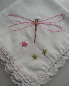 a pink and green dragonfly embroidered on a white handkerchief