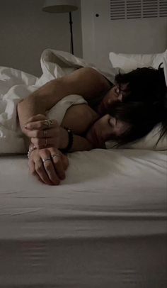 a woman laying on top of a bed next to a man with his arm around her