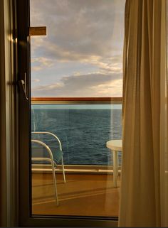 a chair sitting on top of a wooden floor next to a window overlooking the ocean