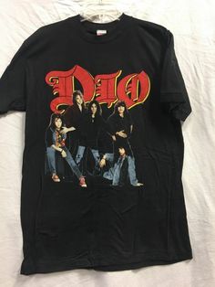 VINTAGE 1980's DIO BAND- ROCK -BLACK, SIZE L , LOCK UP THE WOLVES TOUR T-SHIRT  Size: Large Pit To Pit: 18" Shoulder To Bottom: 33" Backstock 149 NEW CONDITION! SHIPPING DETAILS ***IN HAND & WILL SHIP WITHIN 24 HOURS (1 BUSINESS DAY) OF RECEIVING PAYMENT. I WILL HAPPILY SHIP INTERNATIONALLY BUT BUYER WILL BE RESPONSIBLE FOR ANY ADDITIONAL CUSTOMS FEES, TAXES ETC. CHECK MY FEEDBACK AND PURCHASE WITH CONFIDENCE!*** PAYMENT DETAILS ***PAYPAL ONLY. PLEASE PAY WITHIN 24 HOURS AFTER THE AUCTION/SALE. Rock Band Graphic Tees, Retro Black Top With Band Logo, 70s Band Tees, Dio Band, Heavy Metal Shirt, Metal Shirts, 80s And 90s Fashion, Graphic Tees Vintage, Band Merch