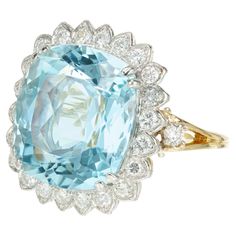 Aqua and diamond cocktail ring. 10.00ct cushion cut center aqua with a halo of 22 round full diamonds set in a two-tone handmade cocktail setting. The untreated sits in a 18k white gold crown with an 18k yellow gold shank accented with two round cut diamonds. Circa 1950's. 1 blue cushion cut aquamarine, VS approx. 10.00cts 22 round full cut diamonds, H-I VS-SI approx. .66cts 2 round full cut diamonds, G-H VS approx. .12cts Size 6.25 and sizable 18k yellow gold 18k white gold Tested: 18k 10.1 grams Width at top: 21mm Height at top: 11.7mm Width at bottom: 1.7mm Aquamarine Cocktail Ring, Antique Wedding Bands, Diamond Sapphire Engagement Ring, Antique Engagement Rings Vintage, Diamond Cocktail Ring, Antique Bracelets, Vintage Sapphire, Diamond Engagement Rings Vintage, Vintage Wedding Band