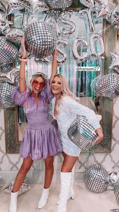 two women posing in front of disco balls