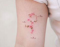 a woman's arm with pink flowers on it and the letter e painted on it