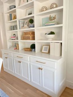 white bookcases with gold handles and drawers in the middle of a living room