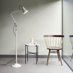 two chairs and a table with a lamp on it in front of a glass wall