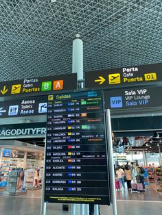 an airport terminal with signs and people walking around