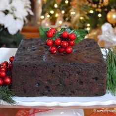 a chocolate cake on a white plate with red berries