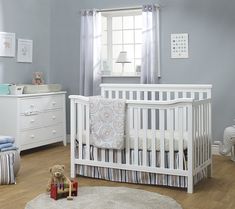 a baby's room with blue walls and white furniture