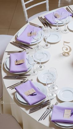 the table is set with purple napkins and place settings for six people to sit at