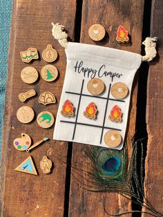 a wooden board with buttons on it sitting next to a peacock feather and a happy camper sign