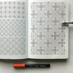 an open notebook with designs on it and a marker next to it, sitting on a table