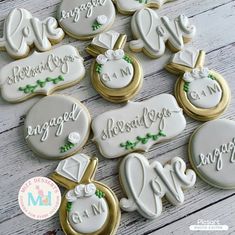 some decorated cookies are sitting on a wooden table with white and gold trimmings