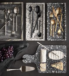 silverware and utensils are laid out on a black tablecloth with speckled designs